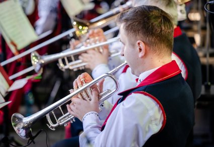 Zbliżenie na Artystów Orkiestry w kostiumach wilanowskich podczas grania na instrumentach dętych