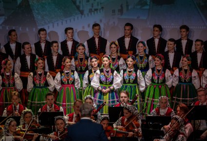 Zbliżenie na solistkę chóru podczas koncertu z widocznych chórem w tle