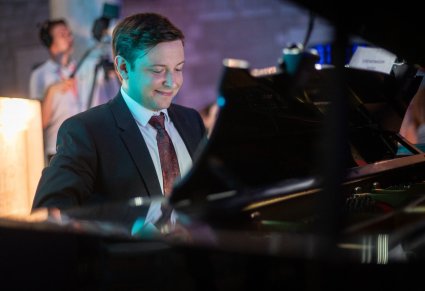 Zbliżenie na lekko uśmiechniętego Akompaniatora grającego na instrumencie