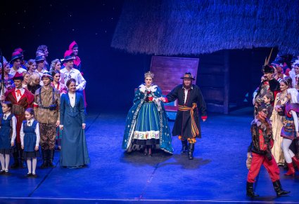 Na środku sceny postacie Matki Boskiej w koronie i królewskiej pelerynie, Św, Józefa a po bokach Artyści występujący w spektaklu