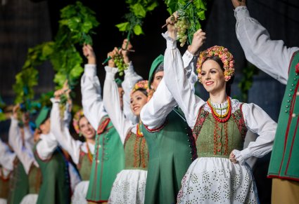 Uśmiechnięci Artyści w kostiumach lubuskich trzymający w górze winorośl