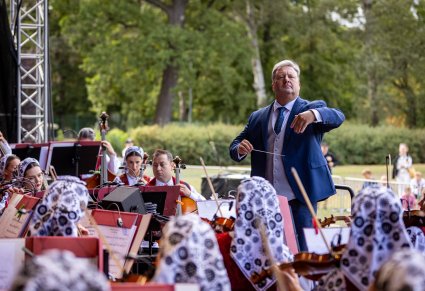 Dyrektor Jacek Boniecki dyrygujący koncert a przed nim orkiestra