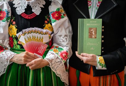 Zbliżenie na artystów w kostiumach kocierzewskich, trzymających egzemplarz "Dziadów"  i pamiątkowe zakładki