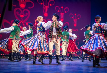 Grupa tancerzy w kostiumach spiskich w obrotach na scenie