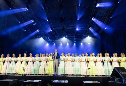 Na pierwszym planie Solista a za nim Artyści Chóru w kostiumach stylizowanych na XIX wiek