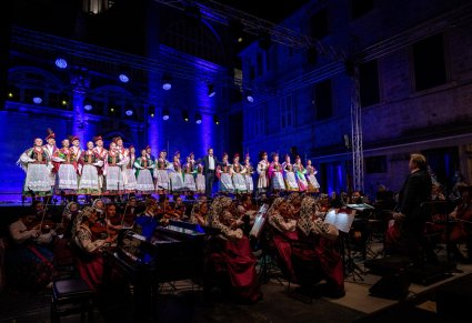 Na pierwszym planie orkiestra a za nią na scenie Artyści z Chóru w kostiumach krakowskich