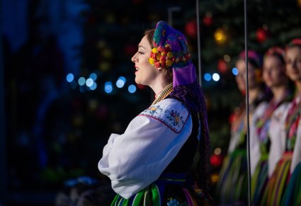 Zbliżenie na śpiewającą Solistkę Chóru w kostiumie łowickim