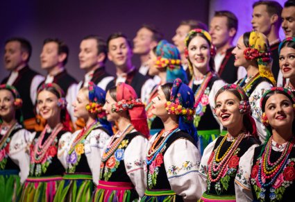 Zbliżenie na uśmiechniętą część Artystów z chóru w kostiumach łowickich