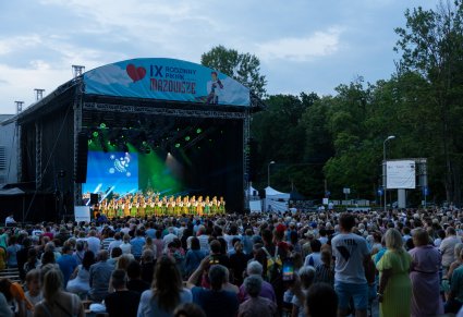 Widok na Scenę plenerową wraz z Publicznością, na scenie Artyści Chóru w kostiumach łowickich a w tle Orkiestra w kostiumach wilanowskich wraz z Dyrygentem