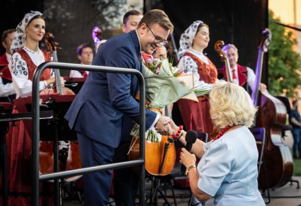 Dyrygent odbiera podziękowania i kwiaty po koncercie.