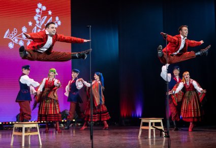 Na scenie dwóch solistów w kostiumach sieradzkich w trakcie wykonywania akrobacji artystycznych
