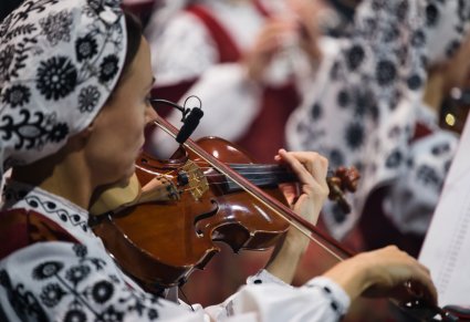 Zbliżenie na Artystkę Orkiestry w kostiumie wilanowskim w trakcie gry na instrumencie smyczkowym