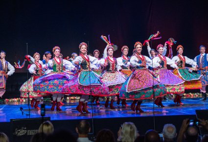 Artyści wykonujący choreografię taneczną na scenie w kostiumach krakowskich