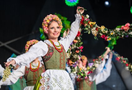 Zbliżenie na Artystkę w kostiumie lubuskim trzymającą dekorację kwiecistą