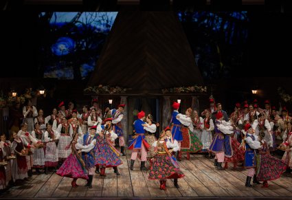 Na środku sceny pary Artystów w kostiumach krakowskich w trakcie wykonywania choreografii tanecznej