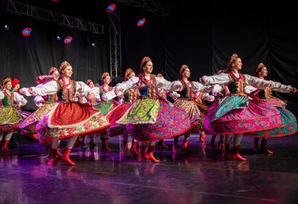 Tancerki w kostiumach krakowskich w obrotach na scenie