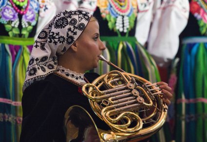 Zbliżenie na Artystkę Orkiestry w kostiumie wilanowskim grającą na waltorni