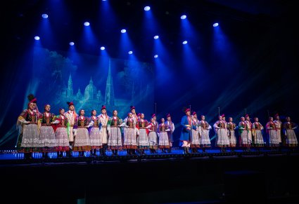 Na scenie Artyści Chóru w kostiumach krakowskich, na środku sceny Solista w trakcie śpiewu