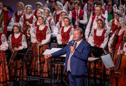 Dyrygent podczas przemowy po koncercie, w tle widoczna orkiestra