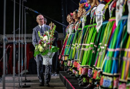 Wójt Gminy Wieliszew przekazujący kwiaty po koncercie, widoczna także część chóru w kostiumach łowickich