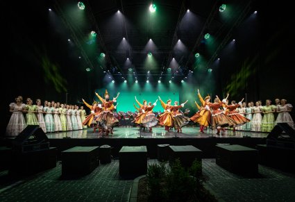 Na środku sceny Artyści Baletu w kontuszach w trakcie wykonywania choreografii tanecznej, po bokach sceny Artyści chóru w kostiumach stylizowanych na XIX wiek