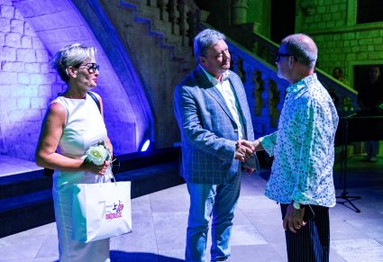 Dyrektor Jacek Boniecki uciskający dłoń innemu mężczyźnie koło niego kobieta zw białej sukience