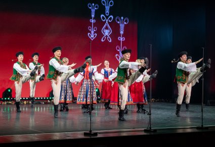 Na scenie Artyści w kostiumach spiskich w trakcie wykonywania choreografii tanecznej