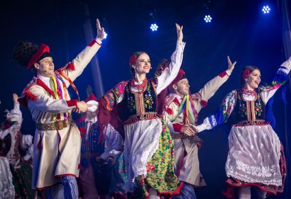 Pary Artystów na scenie w kostiumach krakowskich machający w stronę publiczności