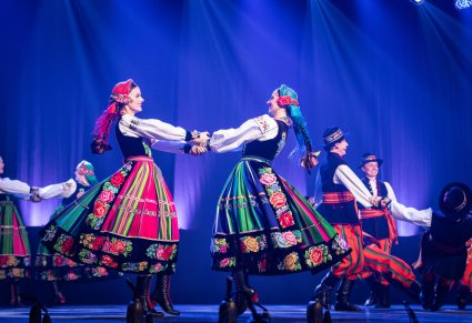 Zbliżenie na tancerki w kostiumach łowickich podczas obrotów na scenie