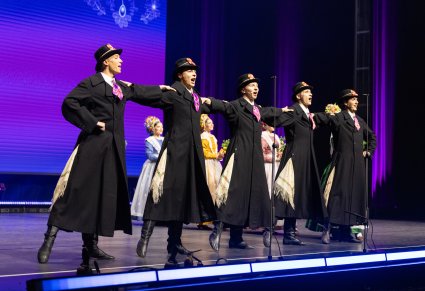 Na pierwszym planie 5 Artystów w kostiumach Bamberskich podczas śpiewu, w tle, za nimi Artystki w kostiumach bamberskich