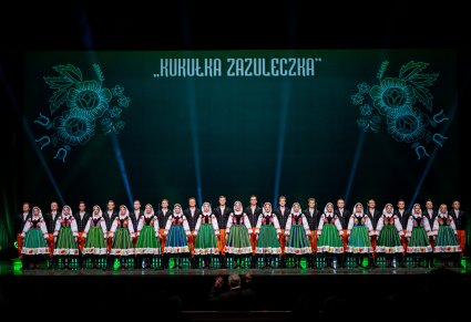 Na scenie Artyści z chóru w kostiumach kocierzewskich w trakcie śpiewu