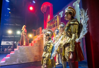 Na pierwszym planie grupa Chóru Wojsk Anielskich w złotych kostiumach, na schodach postać Heroda