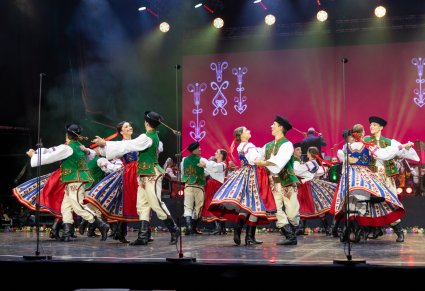 Grupa Artystów w kostiumach spiskich w trakcie wykonywania choreografii tanecznej