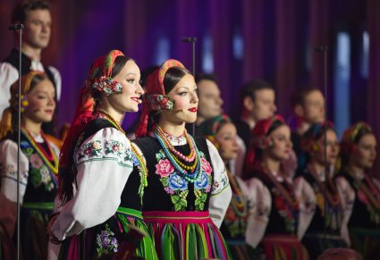 Zbliżenie na dwie Solistki a za nimi pozostała część Chóru w kostiumach łowickich