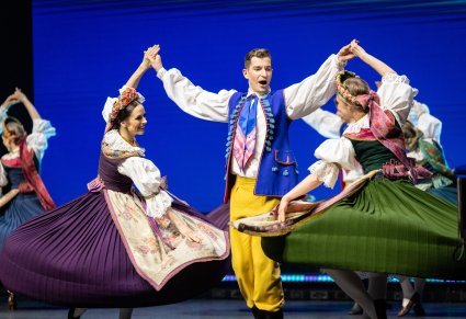 Zbliżenie na trójkę Artystów w kostiumach rozbarskich wykonujących choreografię taneczną na scenie