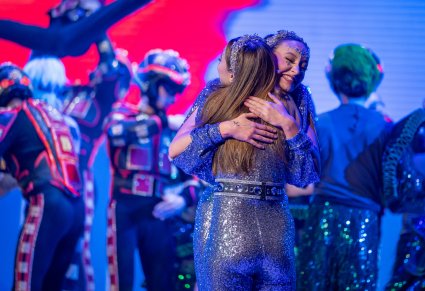 Na pierwszym planie przytulające się postaci głównych gwiazd występujących w spektaklu edukacyjnym "Kolory"