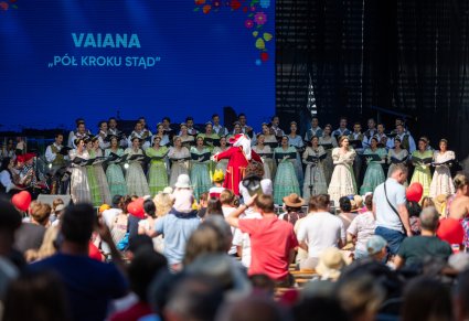 Na scenie Artyści Chóru w kostiumach stylizowanych XIX wiecznych, w ich stronę zwrócony jest Dyrygent, przebrany w kostium Kapitana Hacka