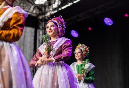 Trzy Artystki w kostiumach bamberskich na scenie wykonujące choreografię taneczną