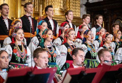 Zbliżenie na część Artystów Chóru w kostiumach łowickich, niżej widoczna część Artystów Orkiestry w kostiumach wilanowskich grająca na instrumentach