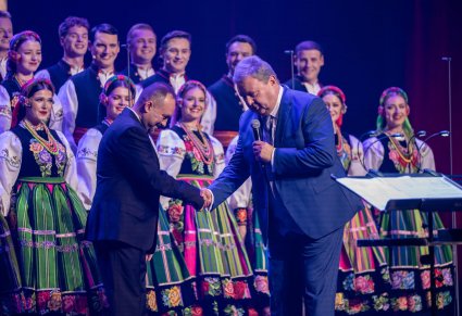 Dyrektor z kierownikiem chóru, w tle widoczny chór