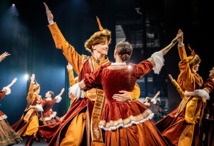 Na pierwszym planie para Artystów w kontuszach, w tle reszta część Artystów wykonująca choreografię taneczną