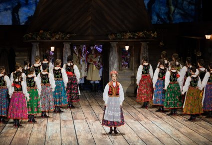Na środku sceny Solistka w kostiumie krakowskim w trakcie śpiewu