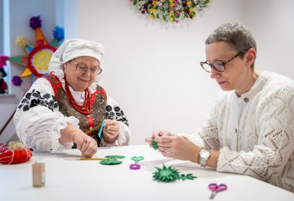 Instruktorka ubrana w strój wilanowski z uczestniczką w trakcie warsztatów rękodzielniczych