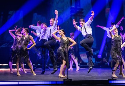 Grupa Tancerzy w kostiumach stylizowanych na lata 20. w trakcie wykonywania choreografii tanecznej