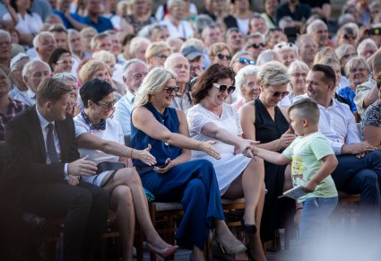 Uśmiechnięta publiczność wyciągająca dłoń do przywitania się z małym chłopczykiem