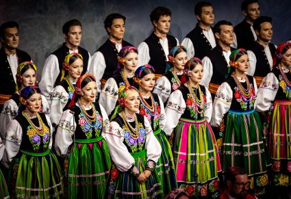 Zbliżenie na część Artystów z chóru w kostiumach łowickich na pierwszym planie Solistka