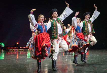 Pary Artystów w kostiumach spiskich podczas wykonywania choreografii tanecznej na scenie