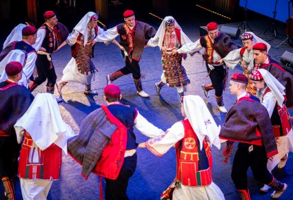 Artyści zespołu z Dubrownika w tradycyjnych kostiumach w trakcie wykonywania choreografii tanecznej na scenie