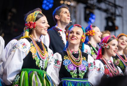Zbliżenie na część Artystów chóru w kostiumach łowickich podczas śpiewu