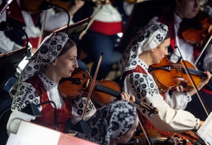 Zbliżenie na artystki orkiestry grające na instrumentach smyczkowych
